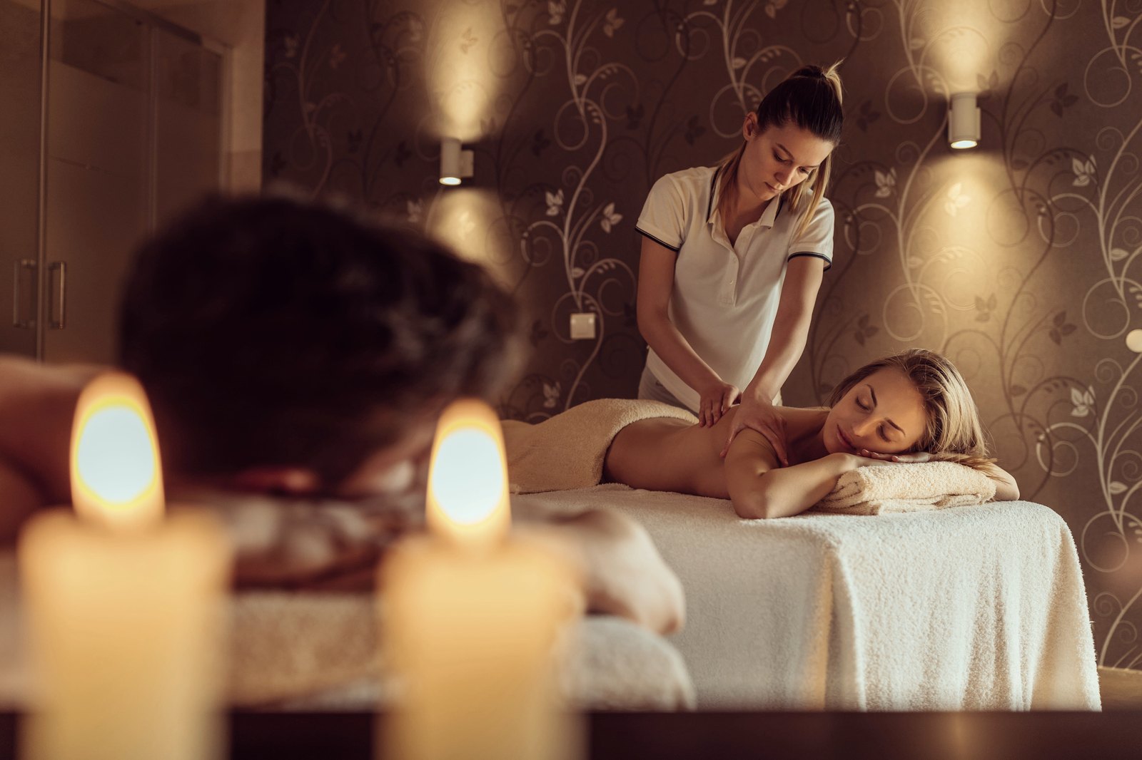 Therapist giving a back massage to a client on a treatment table in a candlelit spa room