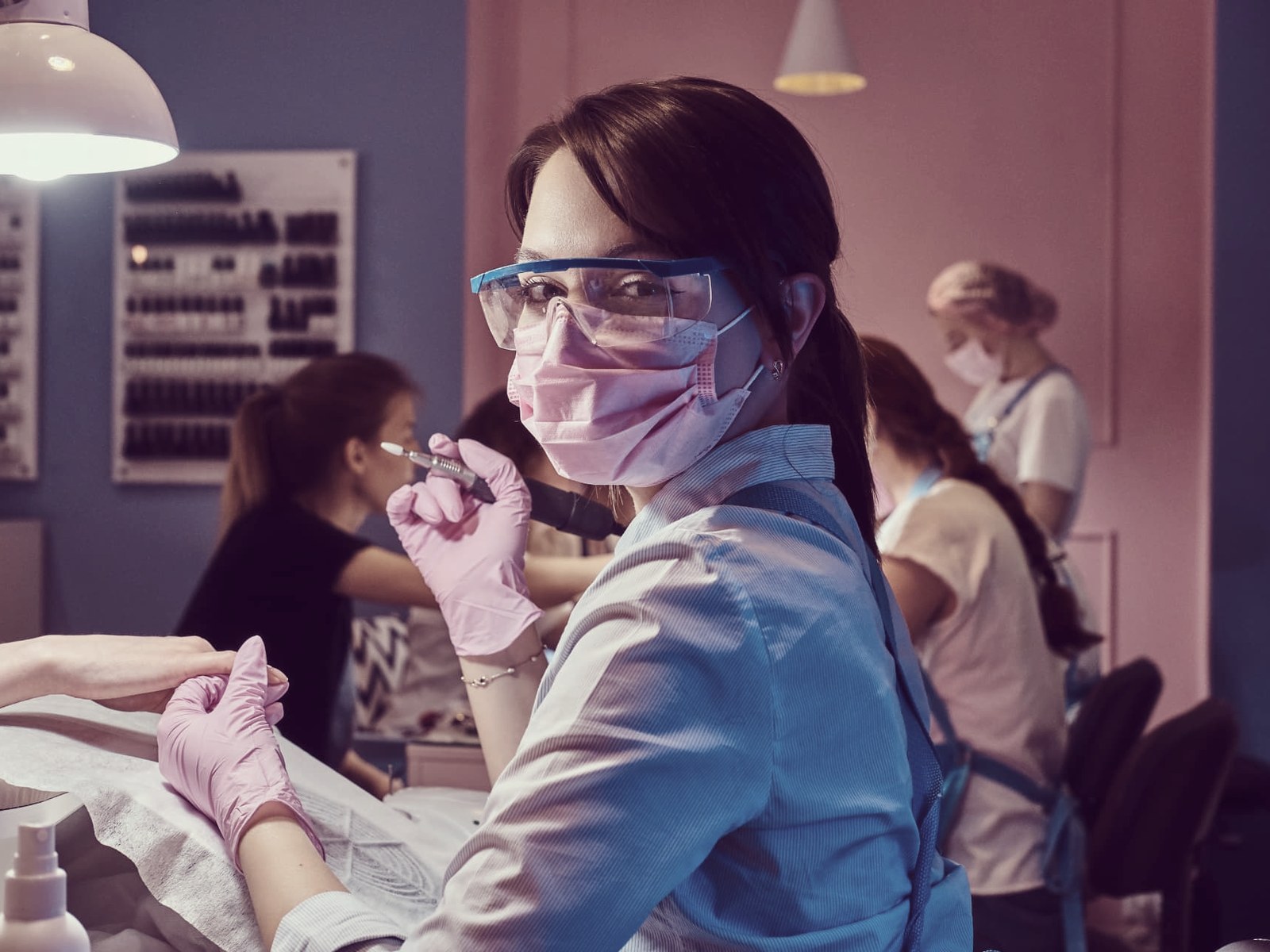 Nail technician working on a client's hands in a busy salon