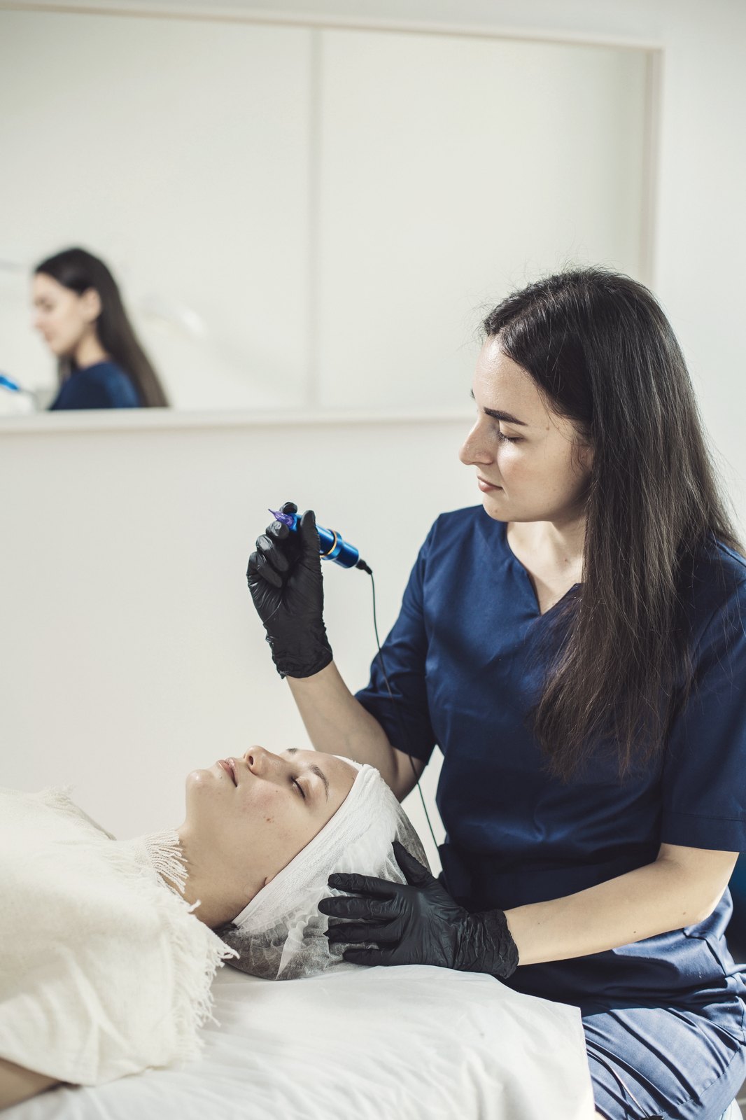 Beautician shaping permanent brow makeup in a bright studio